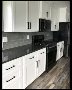 a kitchen with white cabinets and black appliances