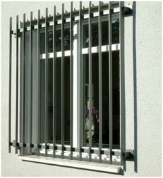 an open window with bars on it and a plant in the window sill next to it