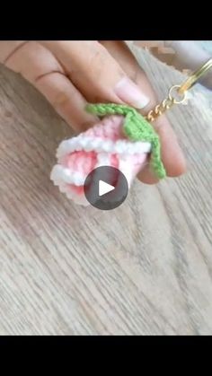 someone is holding a crocheted keychain with a green leaf on it