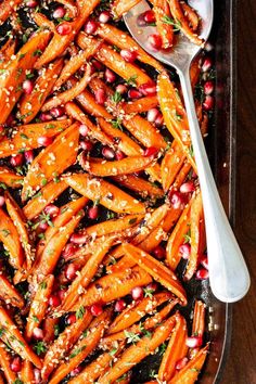 carrots with pomegranate and herbs in a baking dish on a wooden table