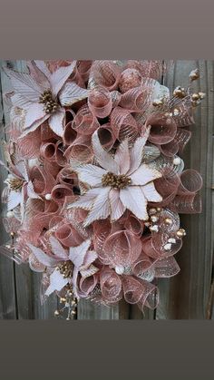 a pink and white wreath hanging on the side of a wooden fence