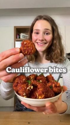 a girl is holding up some meatballs in her hands with the caption cauliflower bites