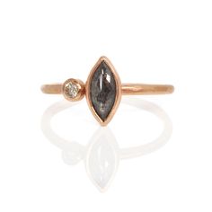 a gold ring with a black diamond and two white diamonds on the front, set in 18k rose gold