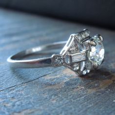 A perfect Art Deco engagement ring. A 1.75 ct Old European Cut diamond (G VS2) is flanked on either side by a baguette diamond (0.14 ct total, F VS1). The entire ring is outlined by 0.30ct of F VS2 round diamonds, bringing the total carat weight to 2.19 ct. The ring is made of platinum. We must say, it is rare to find a high color, high clarity stone and have it be an old fashioned cut. When the modern brilliant first arrived, a lot of people took their good diamonds and had them recut in an eff Old Mine Cut Diamond, Art Deco Engagement, Deco Engagement Ring, Art Deco Engagement Ring, European Cut Diamonds, Platinum Ring, Best Diamond, Baguette Diamond, Nashville Tn