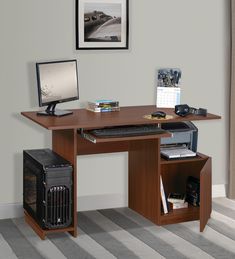 a desk with a computer on top of it in front of a window and striped carpet