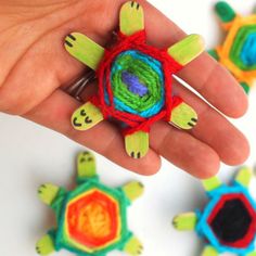 a hand is holding a small crochet tortoise with four smaller turtles in the background