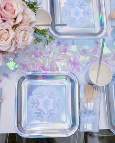 a table topped with silver trays covered in frosted dishes and flowers on top of it