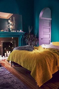 a bedroom with green walls and yellow bedspread in front of a fire place