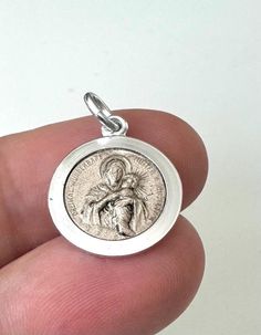 This spiritually significant silver-colored protection pendant celebrates the Thrice Admirable Mother of Schoenstatt, a deep-rooted devotion to Saint Mary and Child Jesus. Measuring 2.4 cm tall and 1.5 cm wide, this pendant is finely crafted, with the front featuring a detailed image of Saint Mary and Child Jesus surrounded by the words "Thrice Admirable Mother of Schoenstatt." The back features another encouraging inscription: "God bless you," making this pendant a powerful symbol of faith and Engraved Spiritual Medallion Jewelry, Sterling Silver Spiritual Jewelry And Charms, Engraved Coin-shaped Spiritual Jewelry And Charms, Nickel-free Spiritual Jewelry And Charms For Gifts, Nickel Free Spiritual Jewelry And Charms For Gifts, Symbolic Miraculous Medal Pendant Jewelry, Engraved White Gold Spiritual Jewelry And Charms, Silver Miraculous Medal Round Pendant, Spiritual Round Pendant Locket