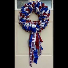 a patriotic wreath is hanging on the front door with ribbon around it's edges