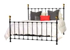 a black iron bed frame with four posts and pillows on top of the headboard