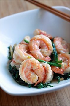 shrimp and spinach stir fry in a white bowl with chopsticks