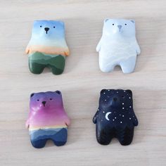 four small ceramic bears sitting on top of a wooden table with stars and moon painted on them