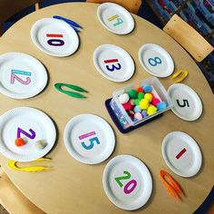 the table has paper plates with numbers on them and plastic candy in front of it