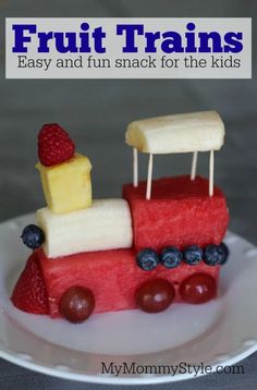 a cake made to look like a train with fruit on the front and sides, sitting on a plate