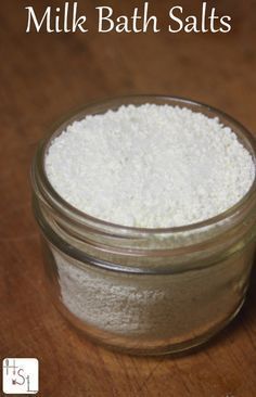 a jar filled with white bath salts on top of a wooden table