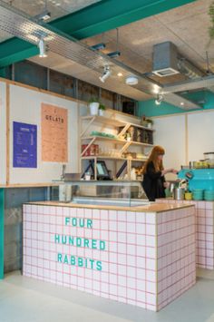 a woman standing in front of a counter with four hundred rabbits written on the wall