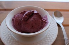 a white bowl filled with purple food on top of a plate next to a spoon