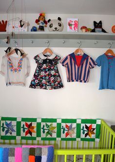 three baby clothes hanging on the wall next to a crib