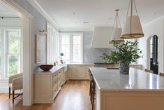 a large kitchen with white cabinets and wood flooring, along with an island in the middle