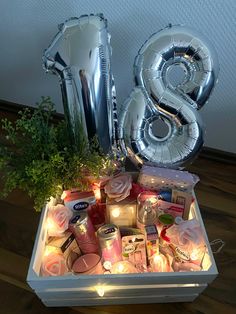 an arrangement of candles, flowers and balloons in a box with the number eight on it