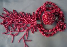 a red beaded necklace with silver beads and an object on the bottom that looks like corals