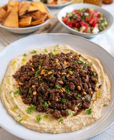 an assortment of food is on a plate with pita bread and other dishes in the background