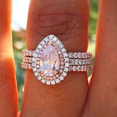 a woman's hand with two engagement rings on top of her finger and an oval shaped