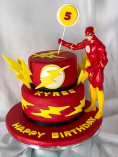 a red birthday cake with the number five on it and a flash man figurine