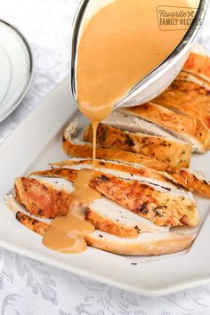 a person pouring sauce onto some chicken on a plate