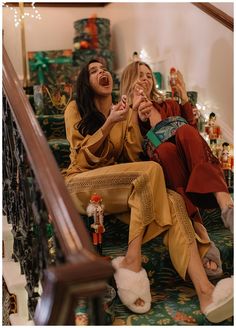 two women sitting on the stairs laughing and having fun with their hands in each other's mouths