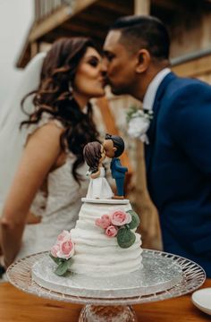 a bride and groom kissing in front of a wedding cake