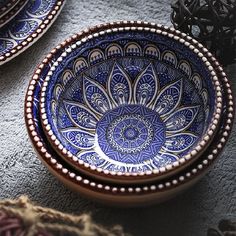 two blue and white bowls sitting next to each other on top of a gray surface