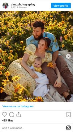 a man and woman sitting on the ground with a baby in their lap, surrounded by sunflowers