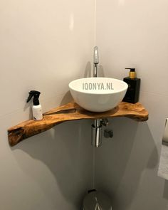 a bathroom sink sitting on top of a wooden shelf in front of a white wall