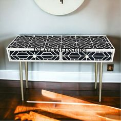 a black and white patterned table sitting on top of a hard wood floor next to a clock