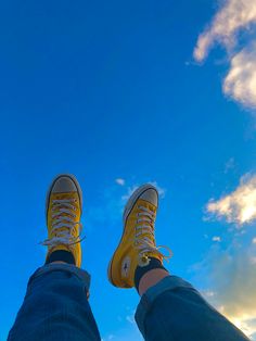 a person wearing yellow sneakers standing in front of a blue sky