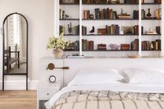 a bedroom with bookshelves and a bed in front of a mirror on the wall