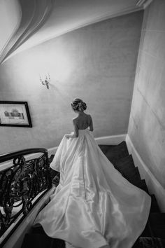 a woman in a wedding dress is walking down the stairs with her back to the camera