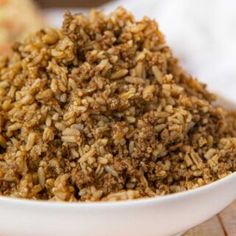 a white bowl filled with brown rice on top of a wooden table