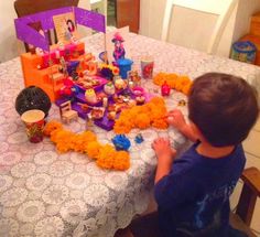 a young boy sitting at a table covered in toys