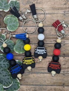 several key chains with cars and tassels attached to them on a wooden surface