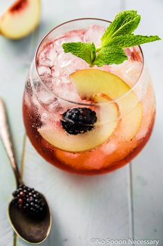 a close up of a drink in a glass with ice and fruit on the side