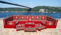 a red couch sitting on top of a wooden floor next to a large body of water