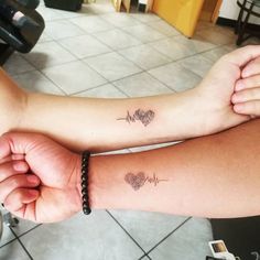 two people with matching tattoos on their arms, one is holding the other's arm