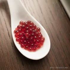 a spoon filled with red jelly on top of a wooden table