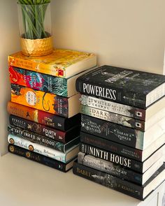 a stack of books sitting on top of a white table next to a vase with flowers