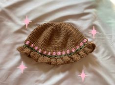 a crocheted hat laying on top of a white bed covered in pink stars