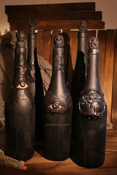 three black bottles with eyes on them sitting next to each other in front of a wooden box