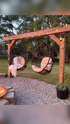 an outdoor fire pit with two hanging chairs